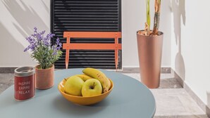 A table with a bowl of fruit, a potted plant, and a candle.