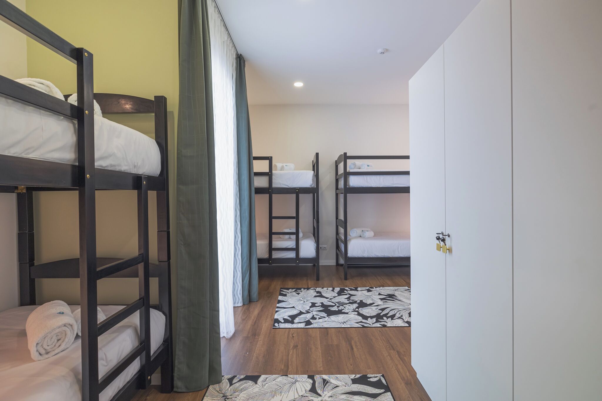 Une chambre avec des lits superposés, une armoire et un tapis à motifs floraux.