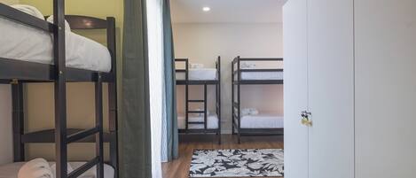 Une chambre avec des lits superposés, une armoire et un tapis à motifs floraux.