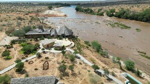 A rural landscape with a river, a few buildings, and sparse vegetation.