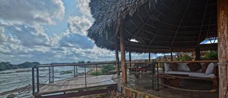 A wooden structure with a thatched roof overlooking a body of water.