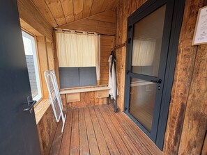 A wooden cabin interior with a bench, a door, and a window.