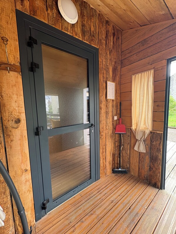 A wooden door with a glass panel, a red floor lamp, and a welcome sign on a wooden wall.