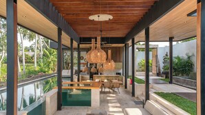 Ein moderner Außenbereich mit Liegebereich, Pool, Holzmöbeln und hängenden Korblampen.