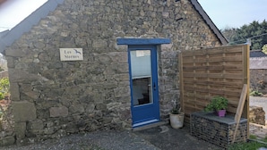 Un bâtiment en pierre avec une porte bleue, une enseigne indiquant « Les Sternes », et une clôture en bois agrémentée de plantes en pot.