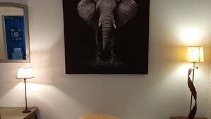 Une chambre à coucher avec un lit, une table de chevet, une lampe et un grand tableau représentant un éléphant accroché au mur.