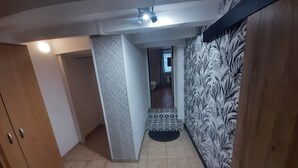 Un couloir avec un mur orné de motifs, une porte en bois et un sol carrelé.