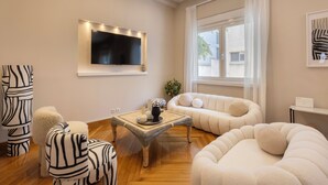 Una sala de estar moderna con un televisor de pantalla plana, un sofá, sillones y una mesa de centro.