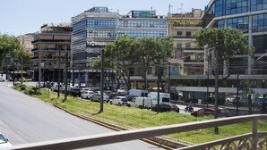 Una calle urbana con edificios modernos, coches aparcados y una acera para peatones.