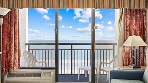 Un balcon avec vue sur la mer, comprenant une table, des chaises et un appareil de climatisation.