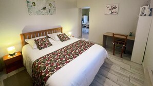 A bedroom with a bed, bedside lamps, a desk, and a chair. - Charming cottage in Montbazon with terrace, garden, and parking (Montbazon)