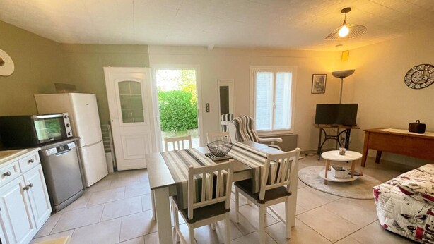 A compact living space with a dining area, kitchenette, and a small seating area with a TV. - Charming cottage in Montbazon with terrace, garden, and parking (Montbazon)