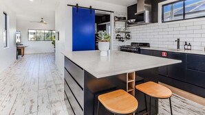 A modern kitchen with a central island, black cabinetry, and a blue accent wall. - Welcome to your perfect holiday retreat! (Tweed)