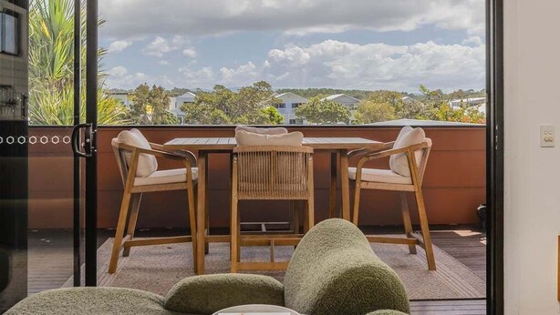 A balcony with a table and chairs, a view of houses, and a cloudy sky. - Welcome to your ultimate holiday getaway! (Tweed)