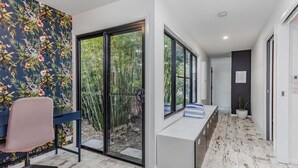 A modern interior with a desk, chair, bench seating, and a view of greenery through large windows. - Welcome to your ultimate holiday getaway! (Tweed)