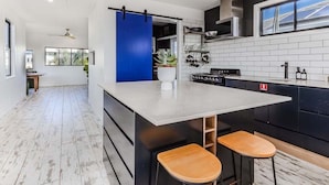 A modern kitchen with a central island, black cabinetry, and a blue accent wall. - Welcome to your ultimate holiday getaway! (Tweed)