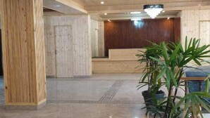 Un vestíbulo amplio con techo de madera, una recepción y plantas en macetas.