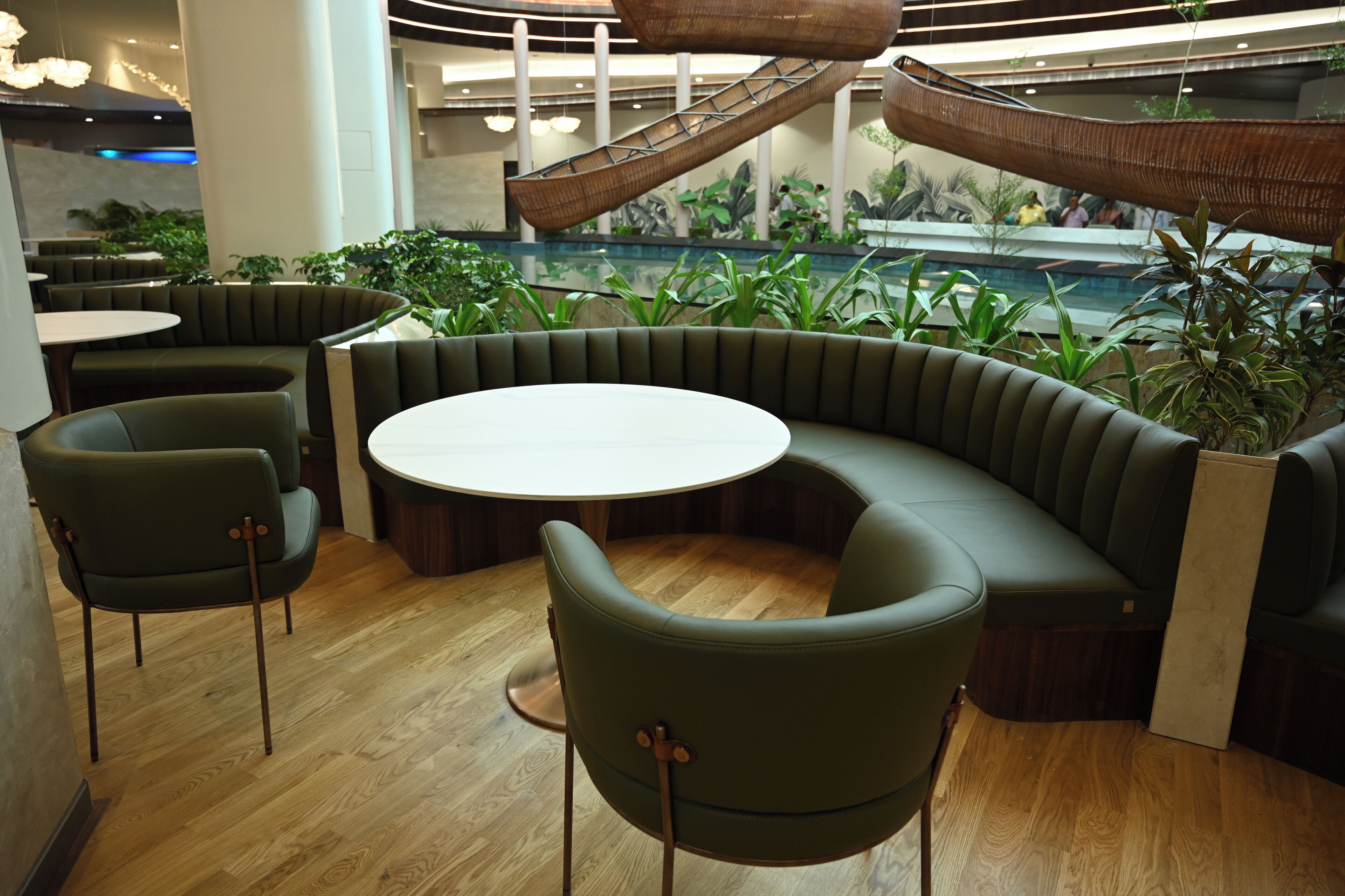 A modern indoor seating area with a round table, cushioned seating, and a central staircase.