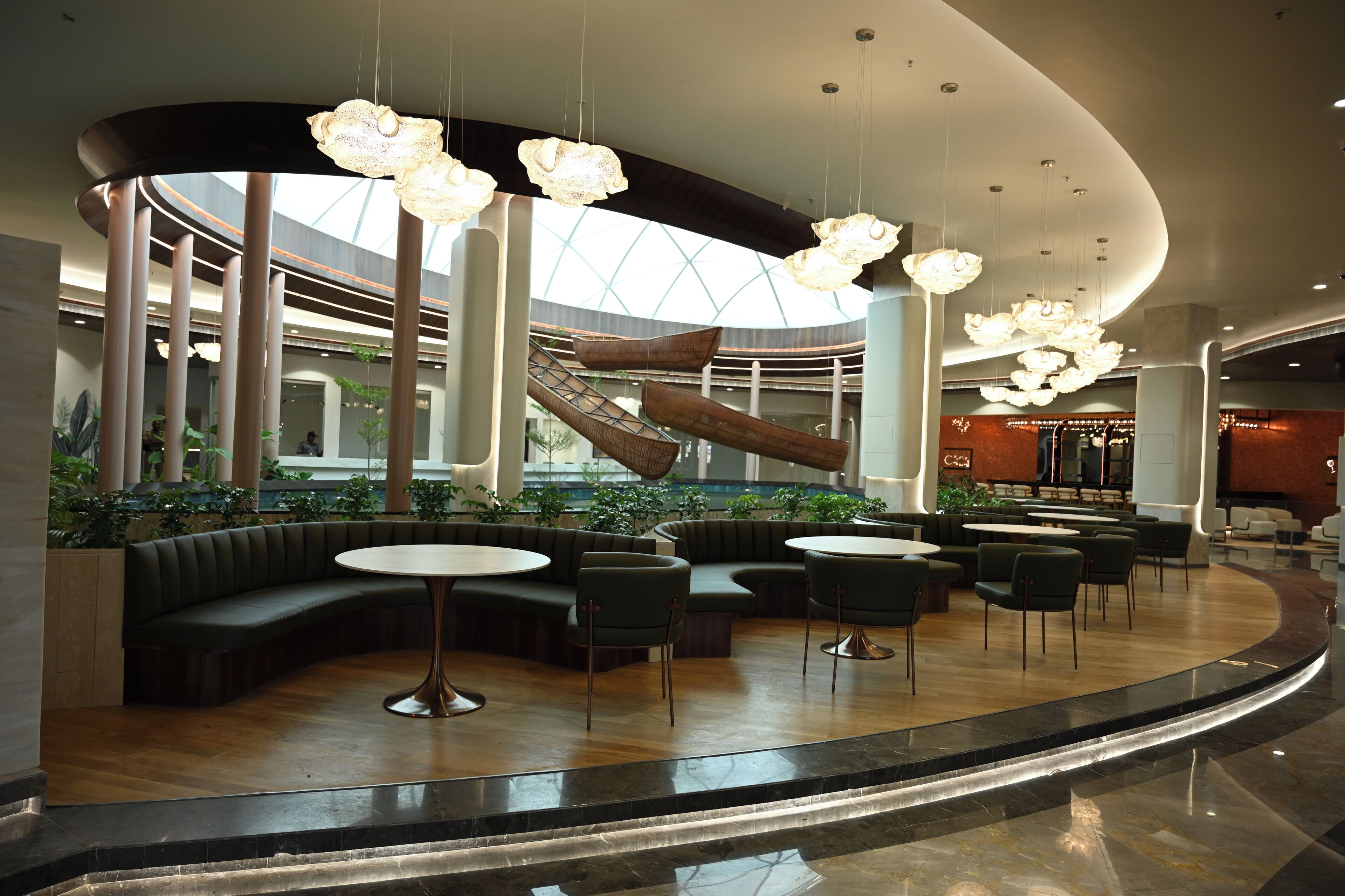 A modern interior with a curved seating area, a central staircase, and hanging light fixtures.
