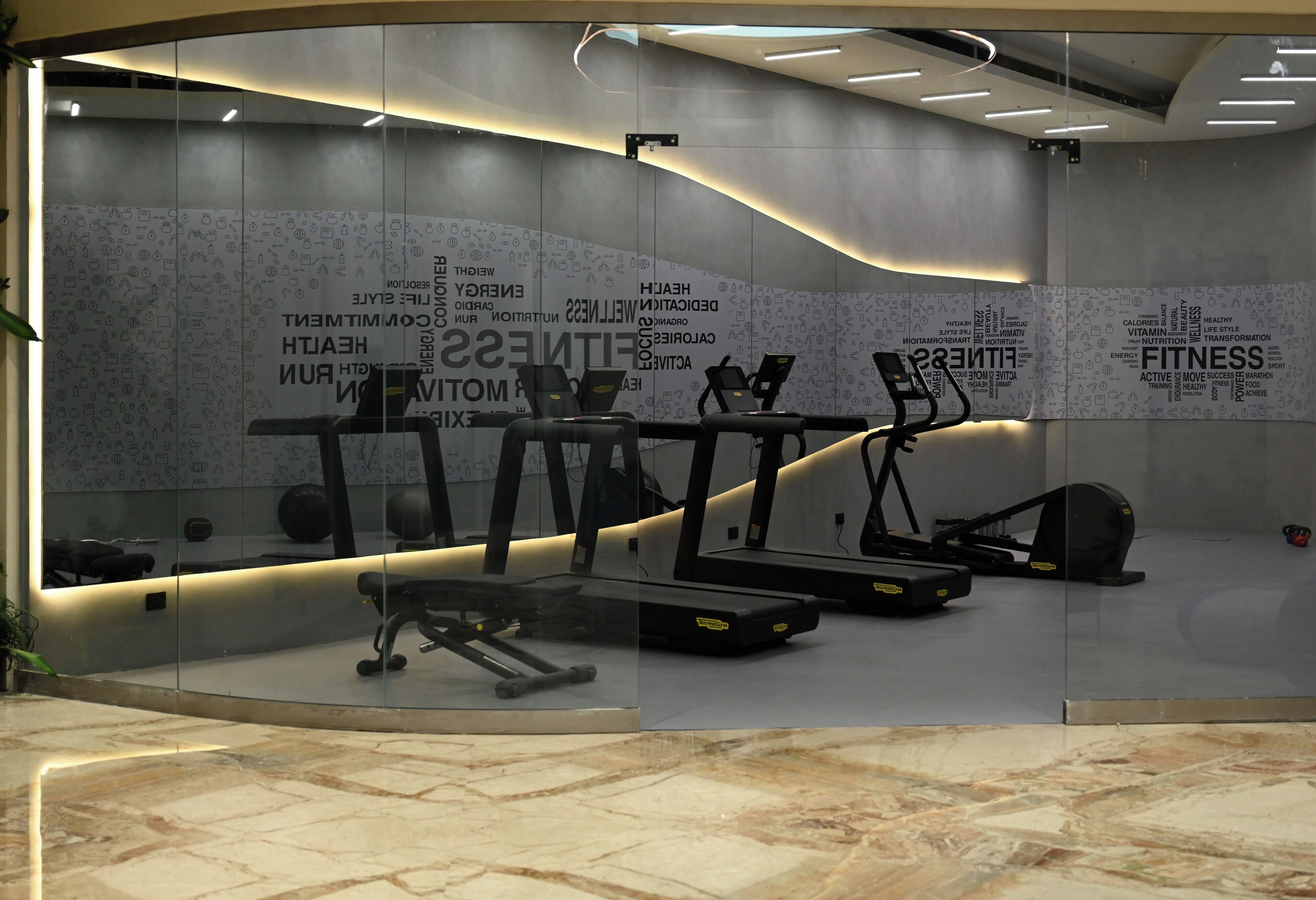 Un gimnasio moderno con cintas de correr, elípticas y bancos de pesas.