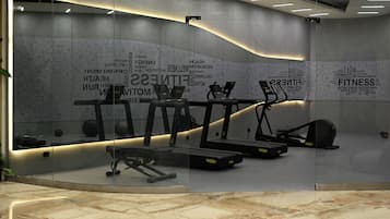 A modern gym with treadmills, elliptical machines, and weight benches.