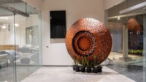 A modern lobby with a large metallic sculpture, glass walls, and a marble floor. - 0484 Aero Lounge - Terminal 2, Cochin Airport Hotel (Aluva)