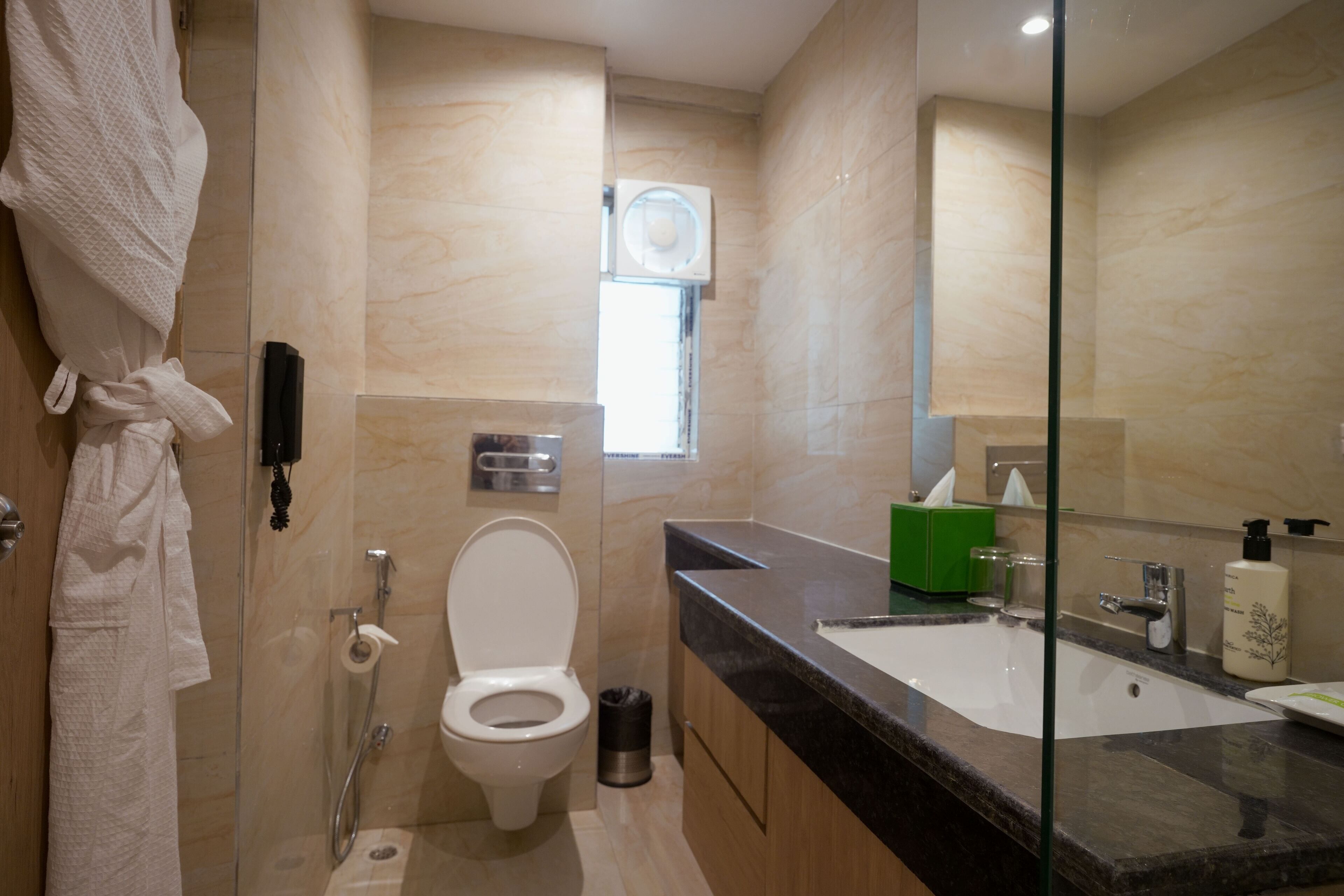 Ein modernes Badezimmer mit Duschkabine aus Glas, Toilette, Waschbecken mit Spiegel und Handtuchhalter.