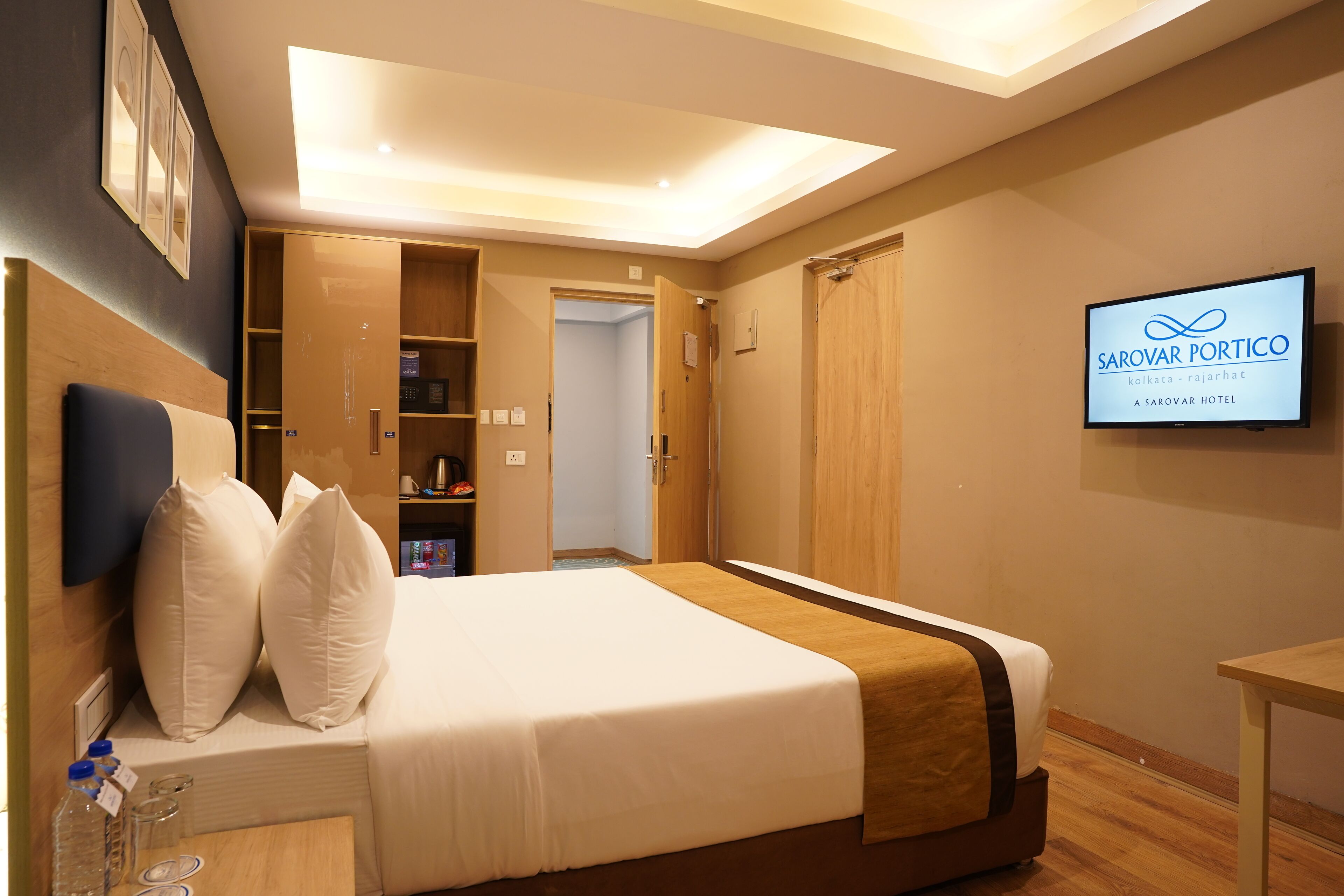 Una habitación de hotel con cama, televisión, armario y una lámpara en el techo.