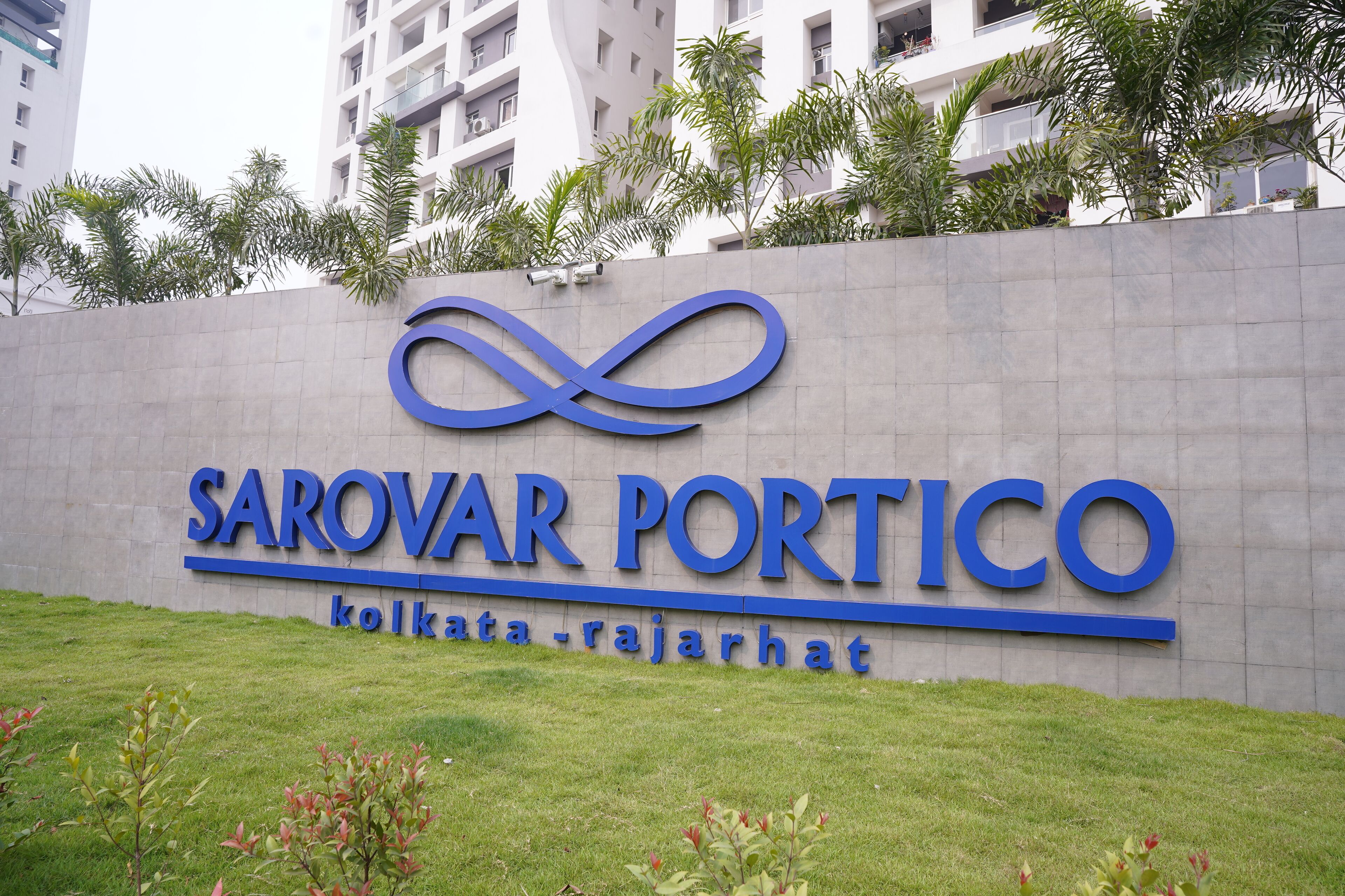 A sign for Sarovar Portico in Kolkata, with a modern design and a logo featuring an infinity symbol.