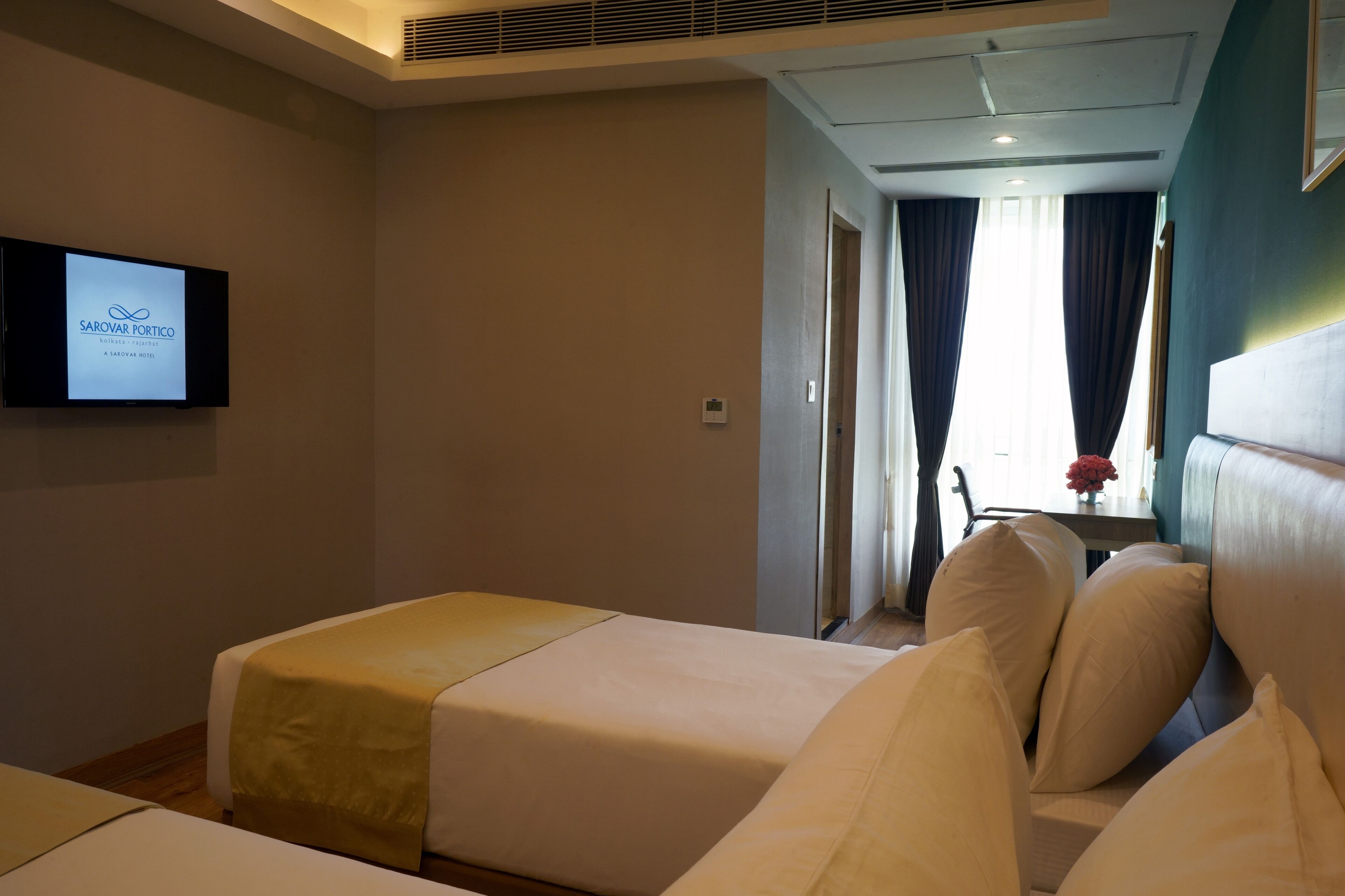 A hotel room with a bed, a television mounted on the wall, and a view of the hallway.