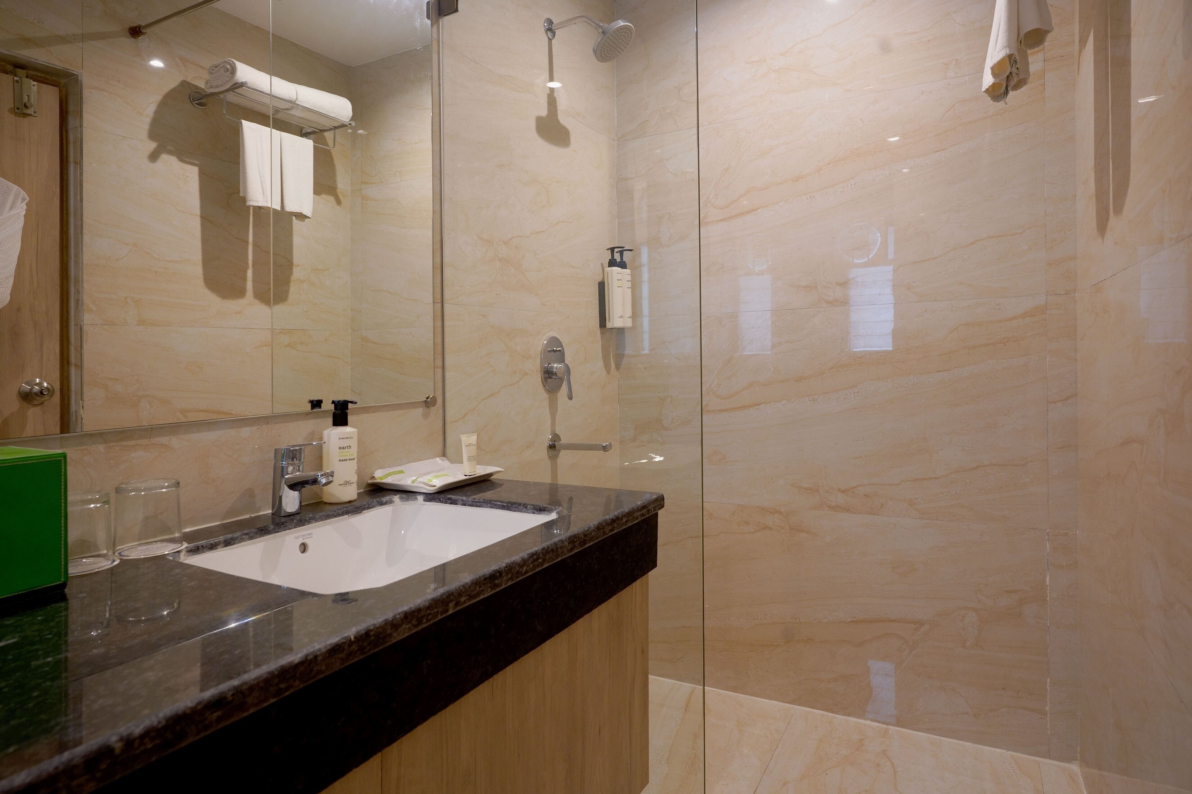 Un baño moderno con ducha acristalada, lavamanos de mármol y un espejo grande.