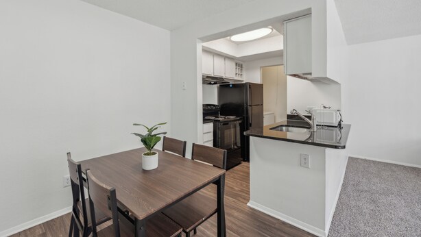 Una cocina moderna con armarios blancos, un refrigerador negro y una isla integrada con fregadero.