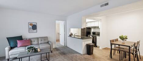 Um apartamento moderno com sala de estar, sala de jantar e cozinha.
