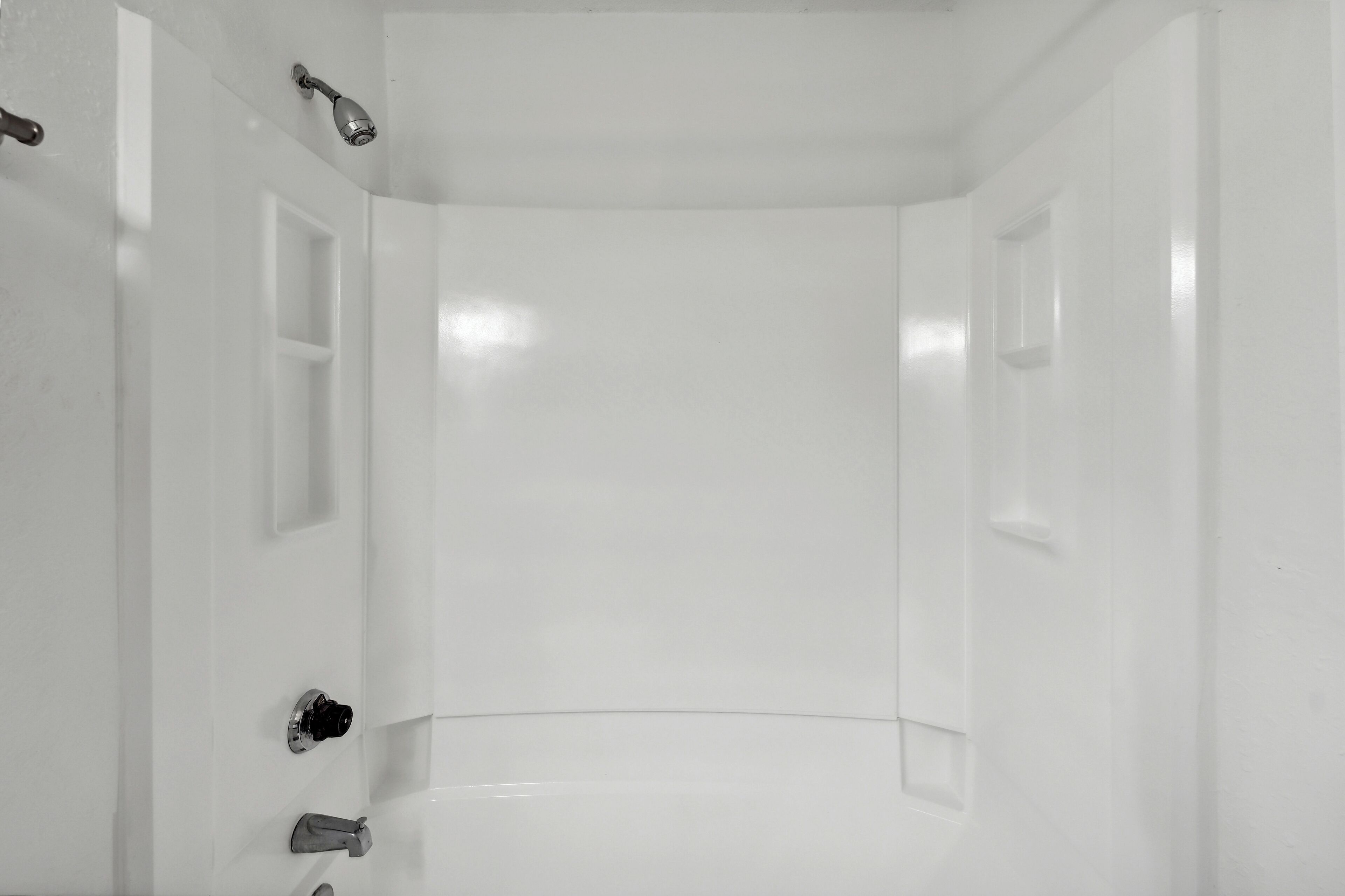 Ein helles, leeres Badezimmer mit Dusche, Toilette und Waschbecken.