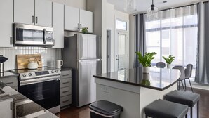 A modern kitchen with stainless steel appliances, a wooden countertop, and a bar area with stools. - Spacious 2BD With Private Balcony and Free Parking 2 (Charlotte)