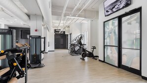 A gym with exercise equipment, a television, and large windows. - Spacious 2BD With Private Balcony and Free Parking 2 (Charlotte)