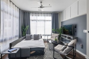 Ein modernes Schlafzimmer mit Bett, Fernseher und Deckenventilator.