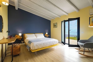 A bedroom with a bed, a desk, a chair, a rocking chair, and a balcony.