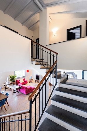 A modern interior with a staircase, a dining area, and a living space.