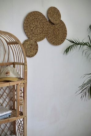 Une chambre avec un lit superposé en bois, une tapisserie murale tissée et une plante en pot.