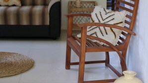 A wooden chair with a patterned cushion, a woven rug, and two ceramic vases on a tiled floor. - Room in Chalet - Amlou Surf House-villa (Mirissa)