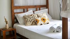 A neatly made bed with white linens, a wooden headboard, and decorative pillows. - Room in Chalet - Amlou Surf House-villa (Mirissa)