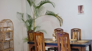 A dining table with four wooden chairs, a woven basket shelf, and a large potted plant. - Room in Chalet - Amlou Surf House-villa (Mirissa)
