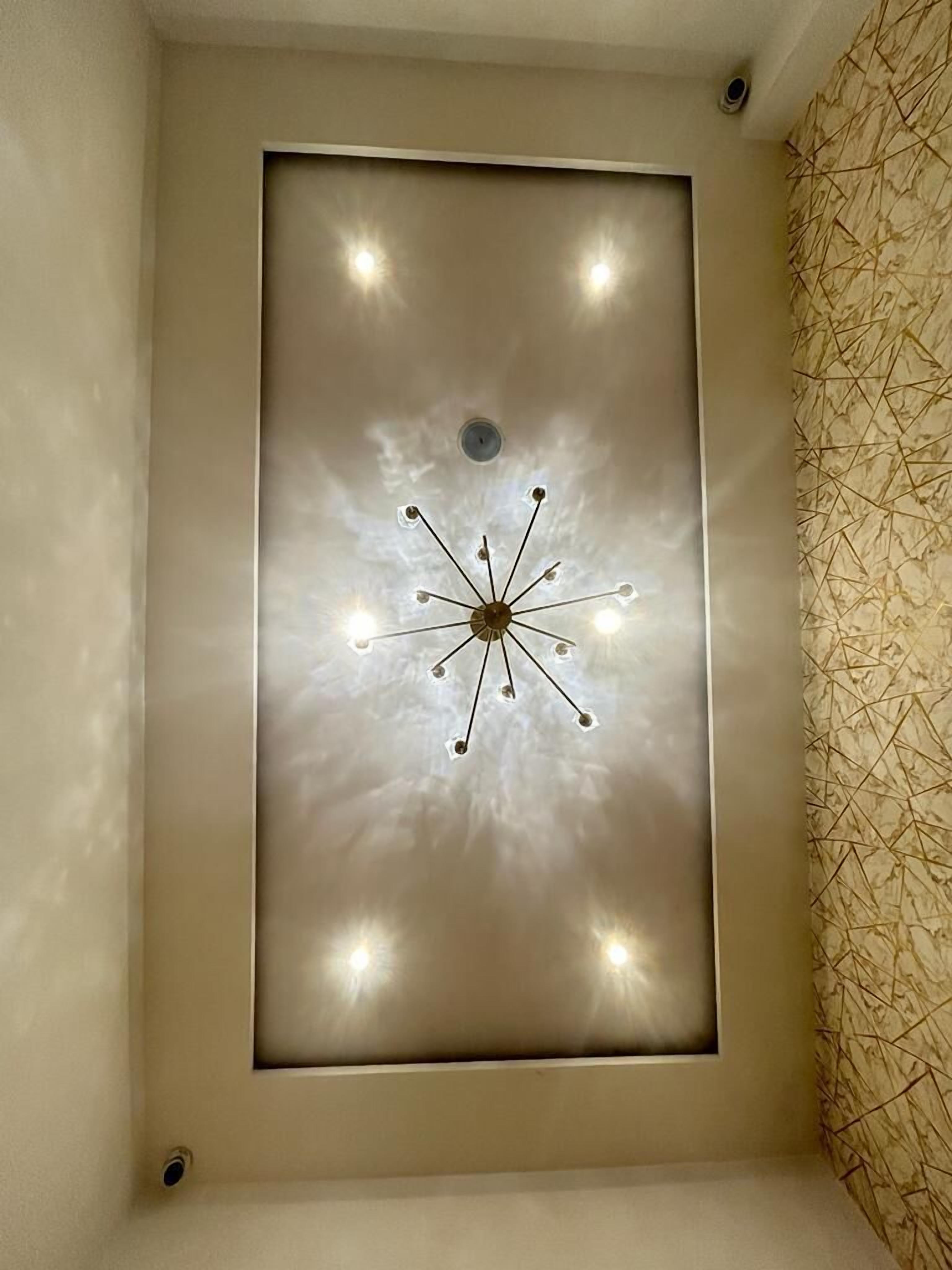 A ceiling with a central light fixture and recessed lighting.