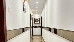 A long, narrow hallway with white walls and a marble floor. - Hotel MIG SUITES (Mumbai)
