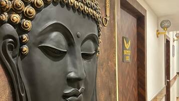 A hallway with a Buddha statue, a sign for 'Suites 103', and a lamp.