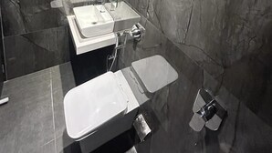 A modern bathroom with dark marble walls, a large mirror, and two sinks. - Hotel MIG SUITES (Mumbai)