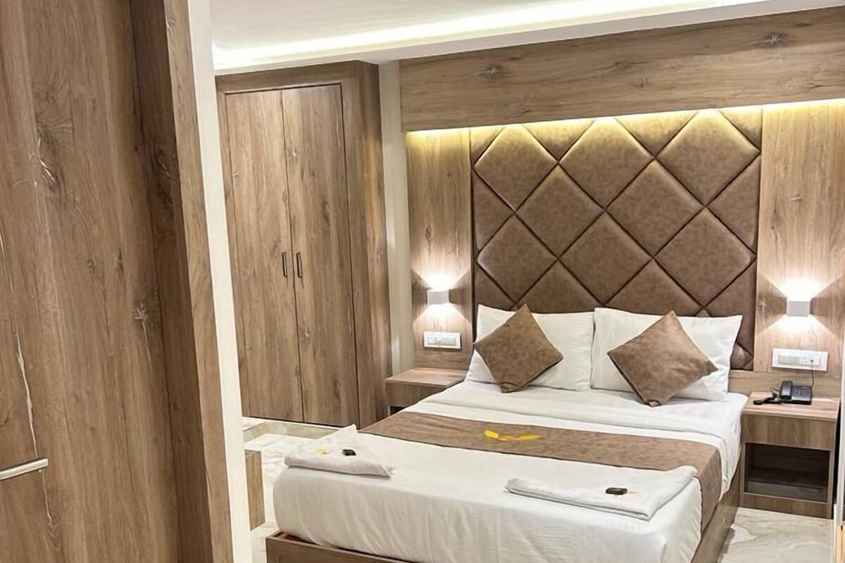 A modern bedroom with a bed, wooden headboard, bedside lamps, and a wooden wardrobe.