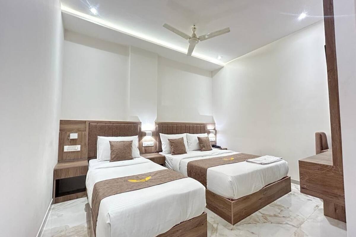 A hotel room with two beds, wooden headboards, bedside tables, and a ceiling fan.