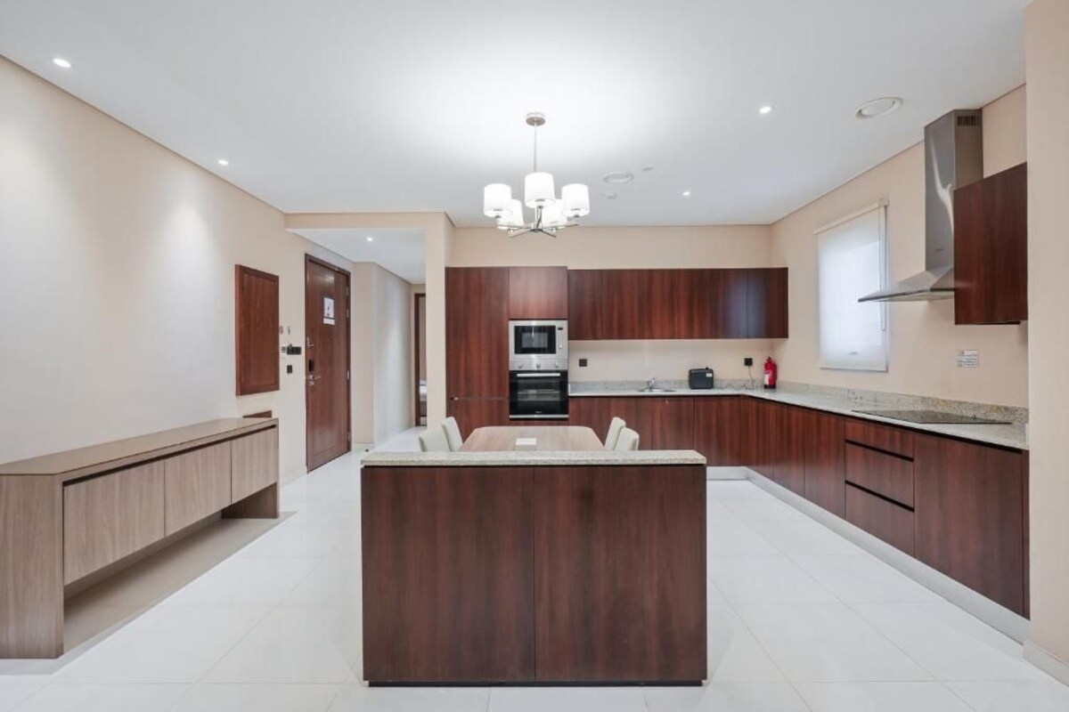 A modern kitchen with a central island, wooden cabinets, and a built-in oven.